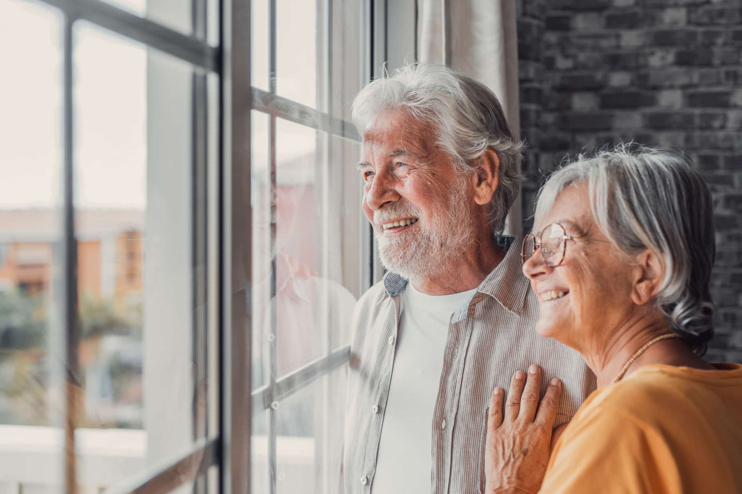 What are The 3 Types of Dental Implants? Happy bonding loving middle aged senior retired couple standing near window, looking in distance, recollecting good memories or planning common future, enjoying peaceful moment together | Aviva Smiles in Henderson, NV